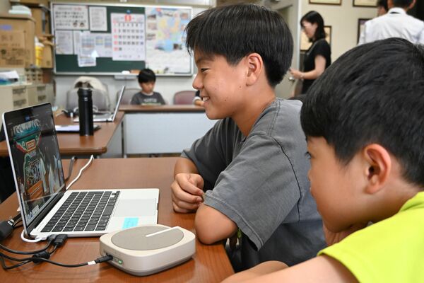 アバターロボットとパソコンをつないで万博会場を見学する壬生小の児童＝27日午後、同校