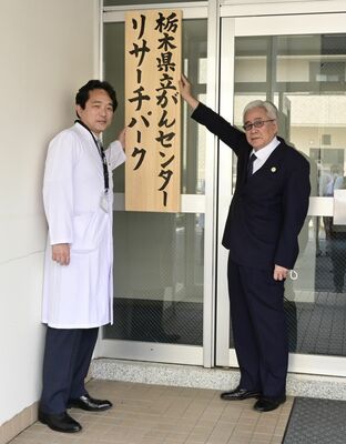 リサーチパークの看板を掲げる尾澤理事長（右）と尾島副所長＝５日午後、宇都宮市陽南４丁目