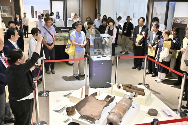 学芸員から展示物の説明を受ける関係者=11日午後2時20分、県立博物館、近藤文則撮影