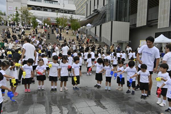 会場の暑さ対策で環境に優しい「打ち水」をする園児たち