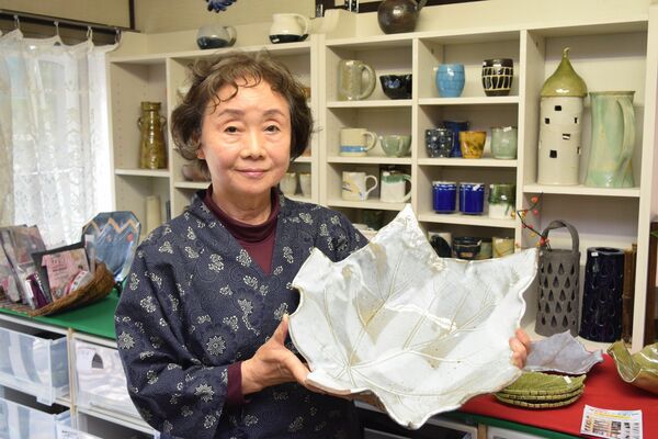 葉っぱの形をした作品を持つ上原さん