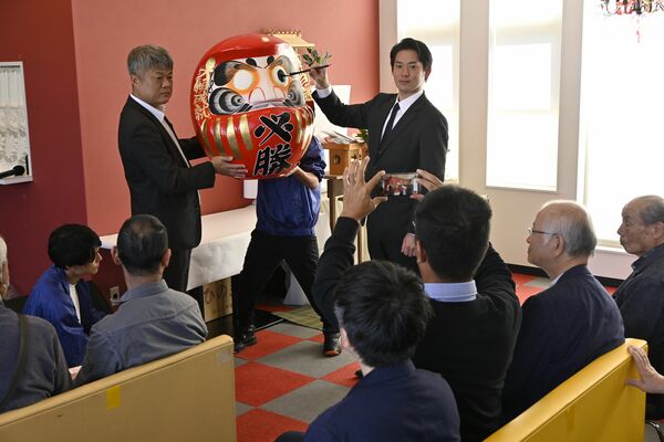 だるまの片目に目を入れる渡辺氏（右）＝12日午前、大田原市末広３丁目