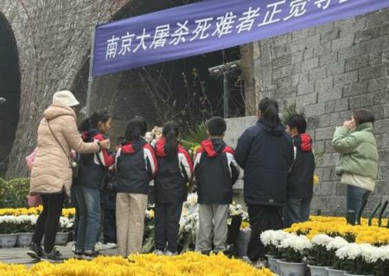 「南京大虐殺」の犠牲者を悼み、献花場で黙とうする子どもたち=13日、中国江蘇省南京(共同)