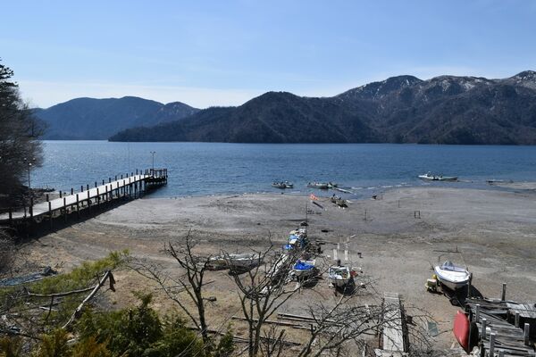 中禅寺湖の水位低下に伴い遊覧船が当面通過することになった菖蒲ヶ浜桟橋（左）周辺。例年であればボートなどがある手前まで水位がある＝11日午前10時20分、日光市中宮祠