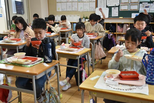 「箒根学園開校お祝い献立」の給食を食べる児童