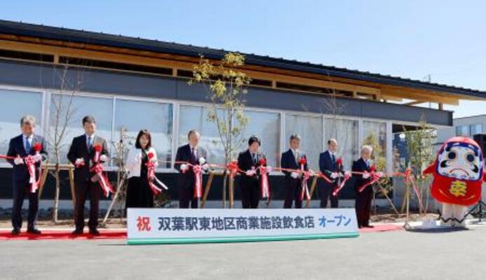 　ＪＲ双葉駅前に完成した商業施設のオープニングセレモニーで、テープカットする伊沢史朗町長（左から４人目）ら＝１４日午前、福島県双葉町