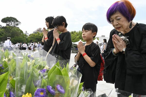平和記念式典後に原爆慰霊碑に手を合わせる小松さん(右)一家=6日午前、広島市中区