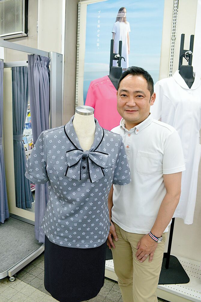 同社の夏服を着用する青木さん(左は女性従業員用)。ボタンダウンのポロシャツは「きちんと見える」と人気