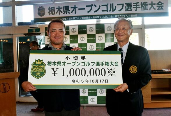 松本大会会長（右）から優勝賞金１００万円の小切手を受け取る佐藤