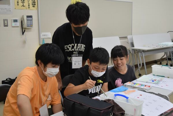 学生ボランティアにアドバイスをもらいながら図工の課題を進める子どもたち