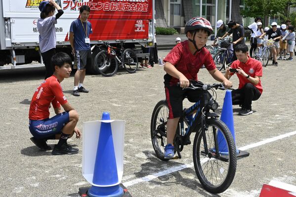 花田選手（左）から正しい自転車の乗り方を教わり出発する児童