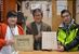 色紙を持つ中村さん（中央）と滝田課長。左の写真は新一さんも写る戦前の小口家の一族写真