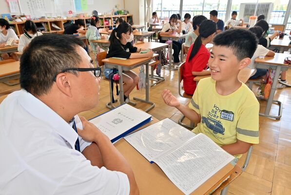 通知表を受け取り、担任教諭と１学期を振り返る児童ら＝20日午前９時55分、野木町友沼