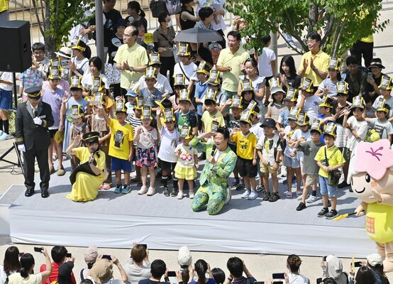 ＬＲＴ開業１周年のイベントで子どもたちの後ろに立ち、ともに祝う佐藤市長（後方中央）。鉄道業界の賞を受賞するなどＬＲＴは高い評価を得ている＝８月25日、宇都宮市宮みらい
