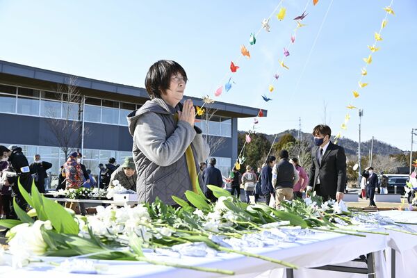 東日本大震災後、初めて「３月11日」を古里で迎えた武内さん。追悼行事で手を合わせた＝11日午後３時、福島県大熊町