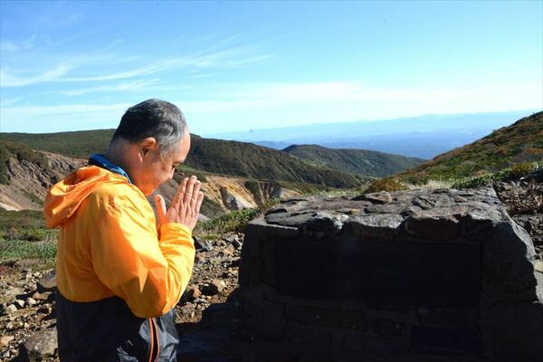 亡くなった４人を悼み、登山道で手を合わせる登山者＝８日午前８時15分、那須町湯本