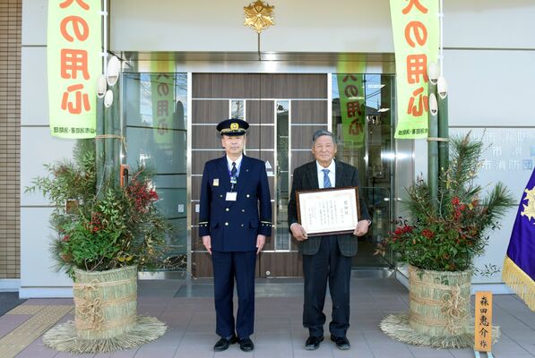 門松の隣で感謝状を手にする森田さん（右）と諏訪消防長