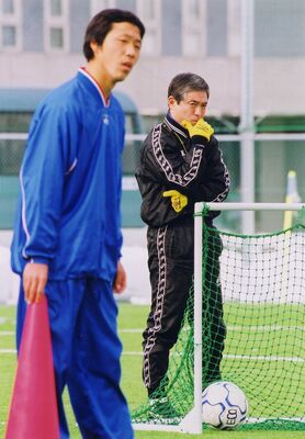 地球環境高（長野）で監督を務め、全国高校選手権初出場に導いた当時の松本さん（奥）＝2002年12月、長野県佐久市
