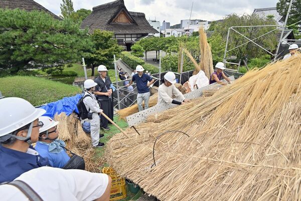 裏門屋根の葺き替え作業を見学する職人ら=12日午前9時25分、足利市昌平町