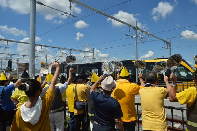 手作りの帽子をかぶり列車を出迎える住民ら=平石TC