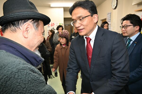 比例で復活当選し支持者と握手する柏倉氏＝９日午前１時５分、宇都宮市峰４丁目