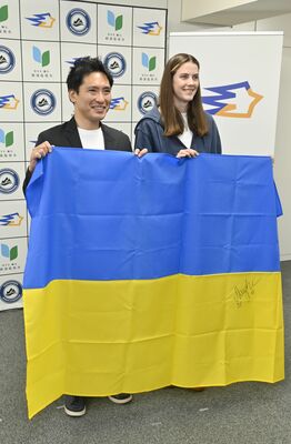 ウクライナ国旗を手にフォトセッションに臨む渡辺市長（左）とマフチフ選手＝14日午後、都内