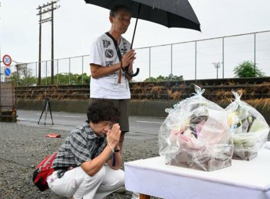 　園の駐車場に設けられた献花台に手を合わせる夫婦＝５日午前、静岡県牧之原市