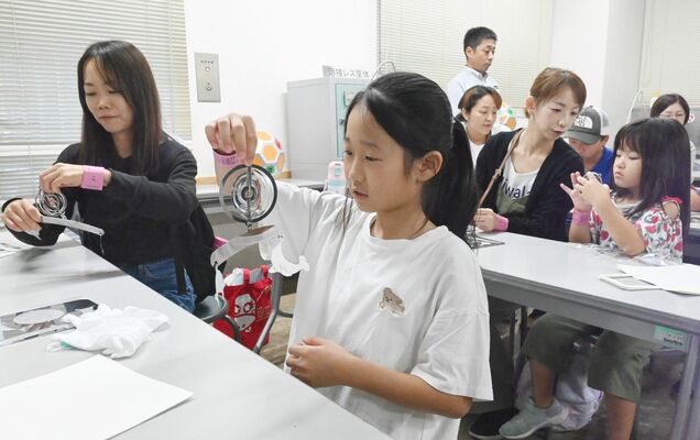 金属製のつり飾りを組み立てる参加者ら