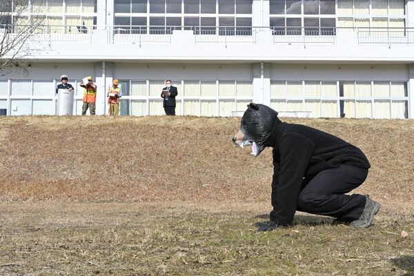 クマ役の職員を相手に、発砲の手順を確認する猟友会メンバーら
