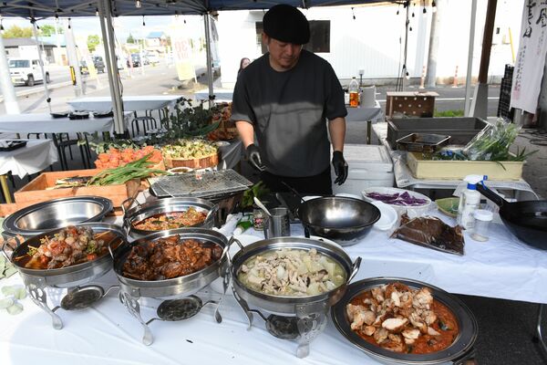 屋外のテントで料理を準備するアンリロの上村シェフ＝６月６日、宇都宮市