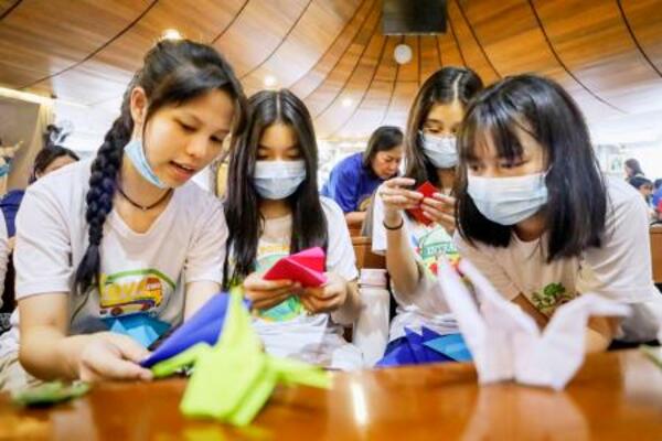 　折り鶴の作り方を話し合う学生ら＝２１日、マニラ首都圏ケソン市（共同）
