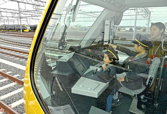 制服を着てＬＲＴの運転席に座り、喜ぶ子どもたち＝20日午後１時25分、宇都宮市下平出町