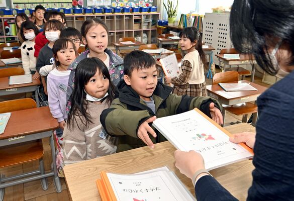 教卓の前に並んで通知表を受け取る児童たち＝25日午後１時５分、鹿沼市上石川
