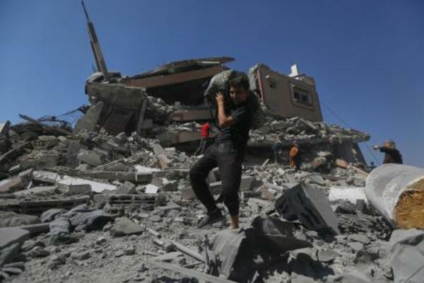 　イスラエルの攻撃を受けたビルのがれきから荷物を運び出す若者＝１２日、ガザ北部ガザ市（ＡＰ＝共同）