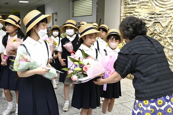 下野新聞社の社員に花束を手渡す作新学院小学部の児童たち＝13日午前、下野新聞社