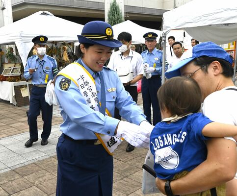 一日警察署長として、来場者に啓発品を手渡す鏡選手＝21日午前、宇都宮市インターパーク４丁目