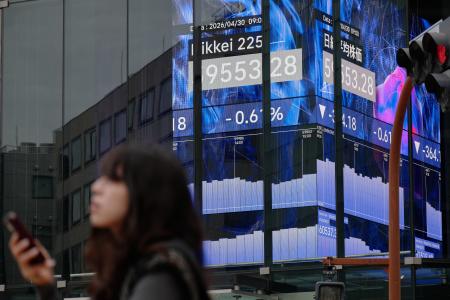 　３０日、電光掲示板の前を歩く人＝東京（ＡＰ＝共同）