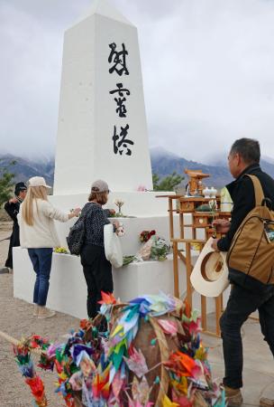 　マンザナー強制収容所跡地の「慰霊塔」で、献花する人たち＝２５日、米カリフォルニア州インディペンデンス（共同）