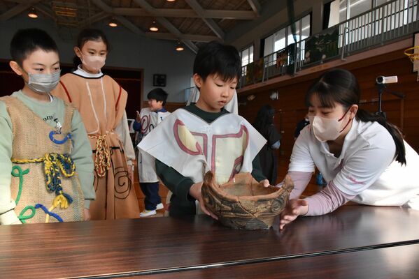 短大生のサポートを受けながら縄文土器に触れる児童
