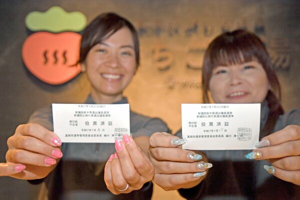 投票済証を手に来館を呼びかけるスタッフ