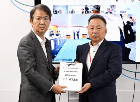 　石原環境相（左）に署名を手渡す「全国公害被害者総行動実行委員会」のメンバー＝３日午前、環境省