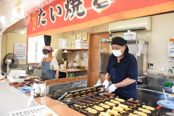 たい焼きを焼く村石一夫さん（右）と、たこ焼きを担当するひろみさん