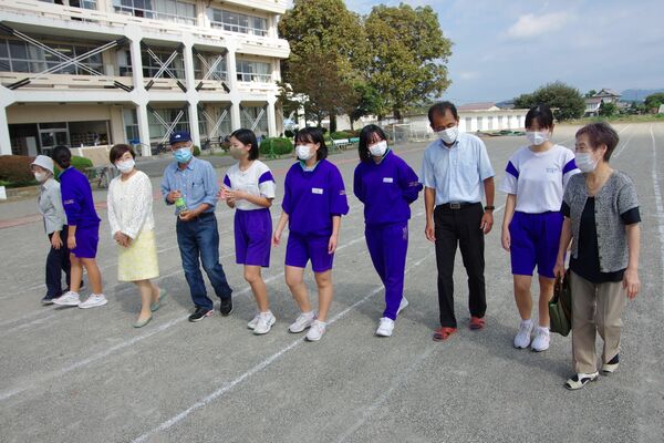 校庭を歩きながら交流する生徒と参加者ら
