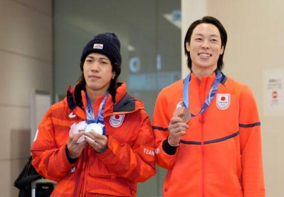 羽田空港に到着し、メダルを手にするノルディックスキー・ジャンプ男子の二階堂蓮(左)と小林陵侑=20日午前