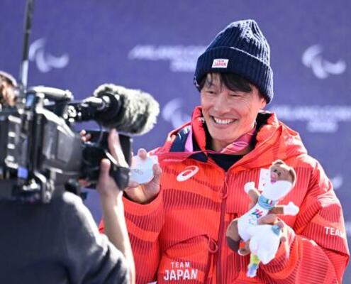 スノーボード男子バンクドスラローム大腿障害の表彰式で、銀メダルとぬいぐるみを手にする小栗大地=13日、イタリア・コルティナダンペッツォ(共同)