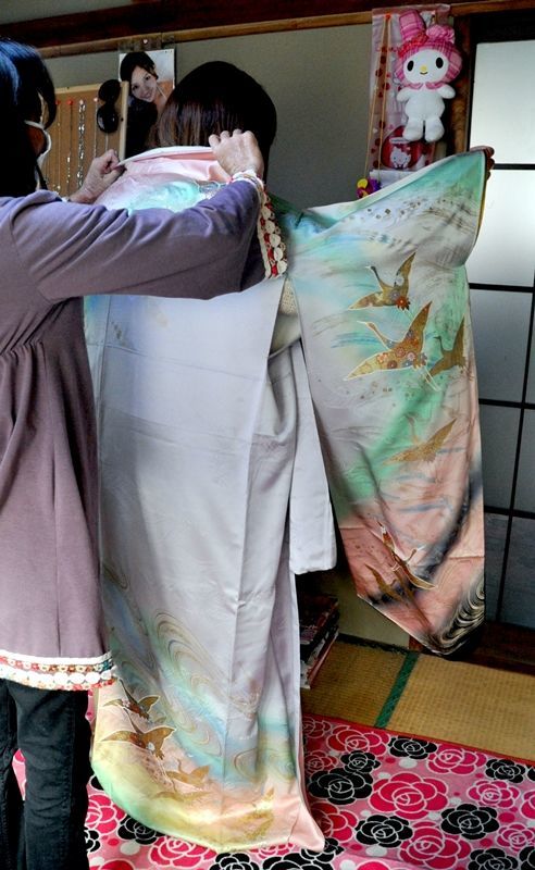 自宅で振り袖に腕を通す未来さん。支援者の氷室さんが未来さんだけの成人式を企画する＝２月上旬、宇都宮市内