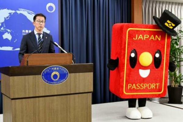 記者会見する北村俊博外務報道官とパスポートのイメージキャラクター「パスポくん」=5月、外務省