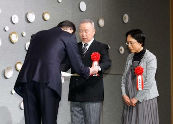 「2025年 シチズン・オブ・ザ・イヤー」に選ばれ表彰を受ける置田和永さん(中央)と起美さん(右)夫妻=29日午前、東京都千代田区