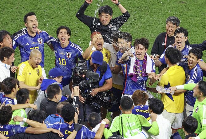 スペインに逆転勝利で決勝トーナメント進出を決め、喜ぶ選手を笑顔で見守る上野氏(右奥)=ドーハ