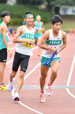 男子文星付の３区小野崎（左）からたすきを受けた４区鈴木が走り出す＝前橋総合運動公園群馬電工陸上競技・サッカー場＝鈴木航撮影